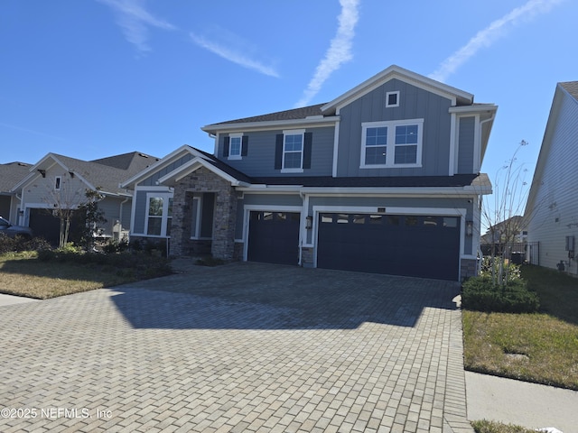 craftsman-style house with a garage, stone siding, board and batten siding, and decorative driveway