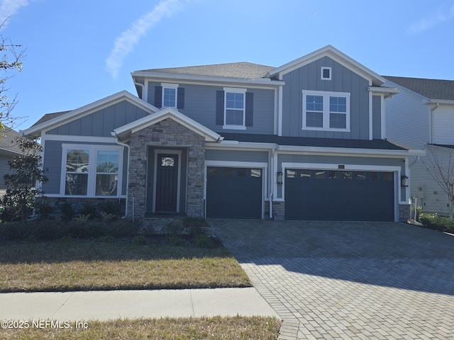 craftsman inspired home with decorative driveway, stone siding, board and batten siding, and an attached garage