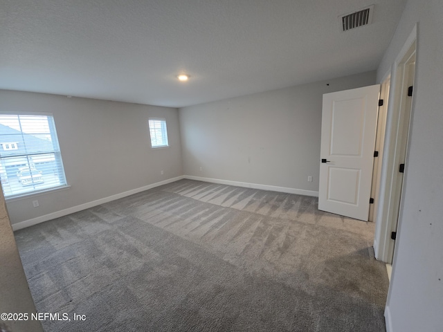 spare room featuring visible vents, carpet floors, and baseboards