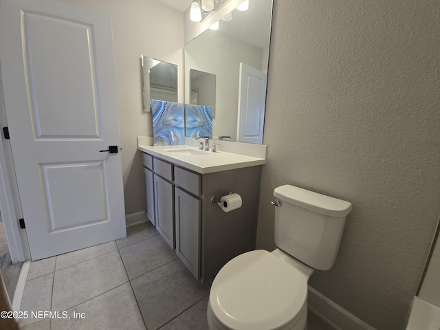 bathroom with vanity, toilet, a textured wall, and tile patterned flooring