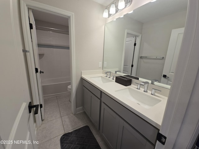 full bathroom featuring tile patterned flooring, vanity, tiled shower / bath, and toilet