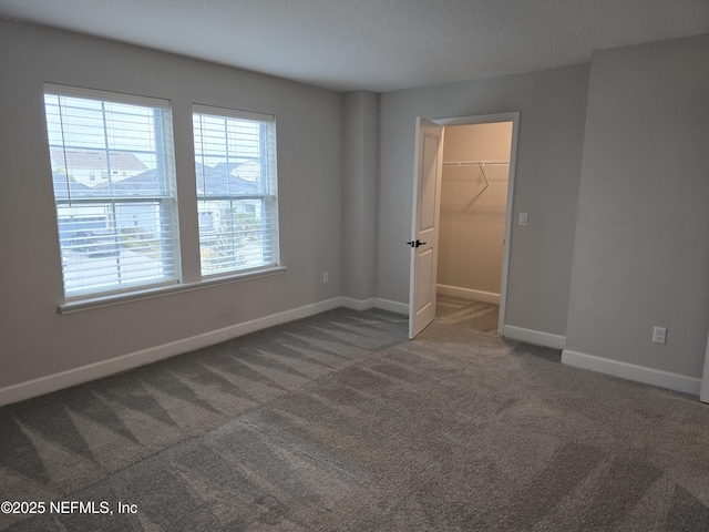 empty room with dark carpet, a textured ceiling, and a healthy amount of sunlight