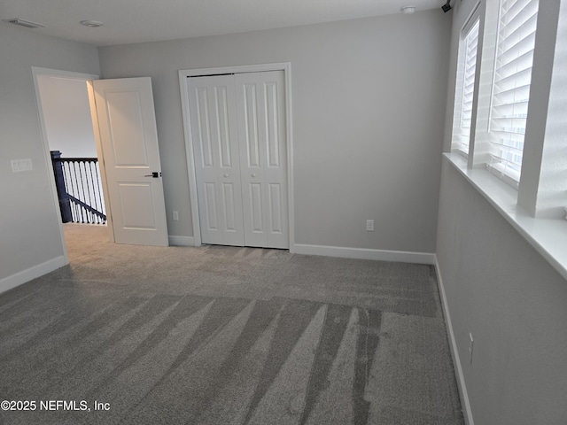 unfurnished bedroom featuring visible vents, baseboards, carpet, and a closet