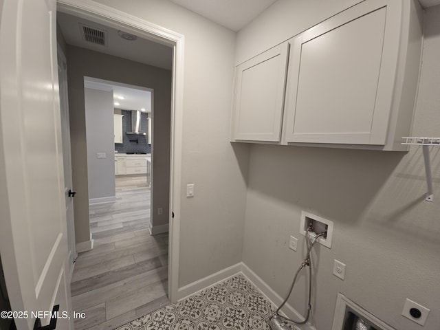 laundry area with cabinets, electric dryer hookup, washer hookup, and light hardwood / wood-style flooring