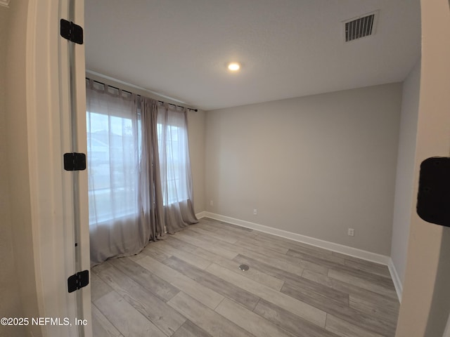 unfurnished room featuring visible vents, light wood-style flooring, and baseboards