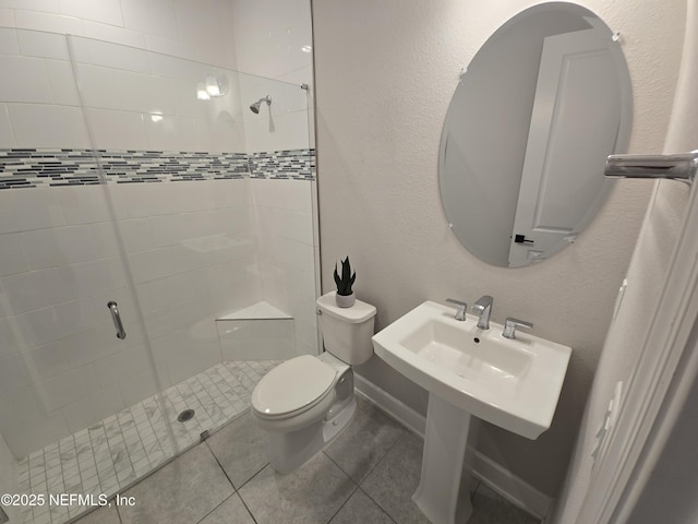 full bathroom featuring baseboards, tile patterned flooring, a shower stall, toilet, and a textured wall