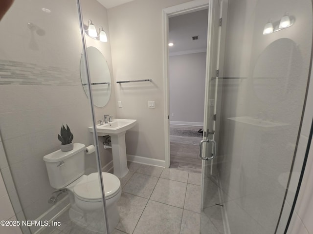 bathroom featuring crown molding, toilet, a shower with door, and tile patterned flooring