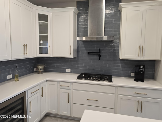 kitchen featuring wine cooler, wall chimney exhaust hood, and white cabinetry