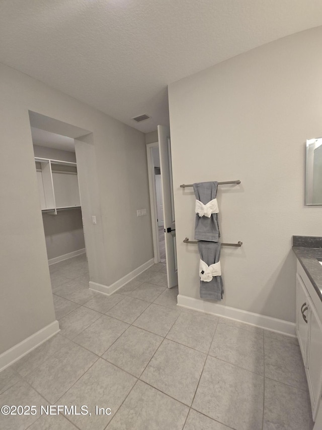 bathroom with tile patterned floors, visible vents, a textured ceiling, baseboards, and vanity