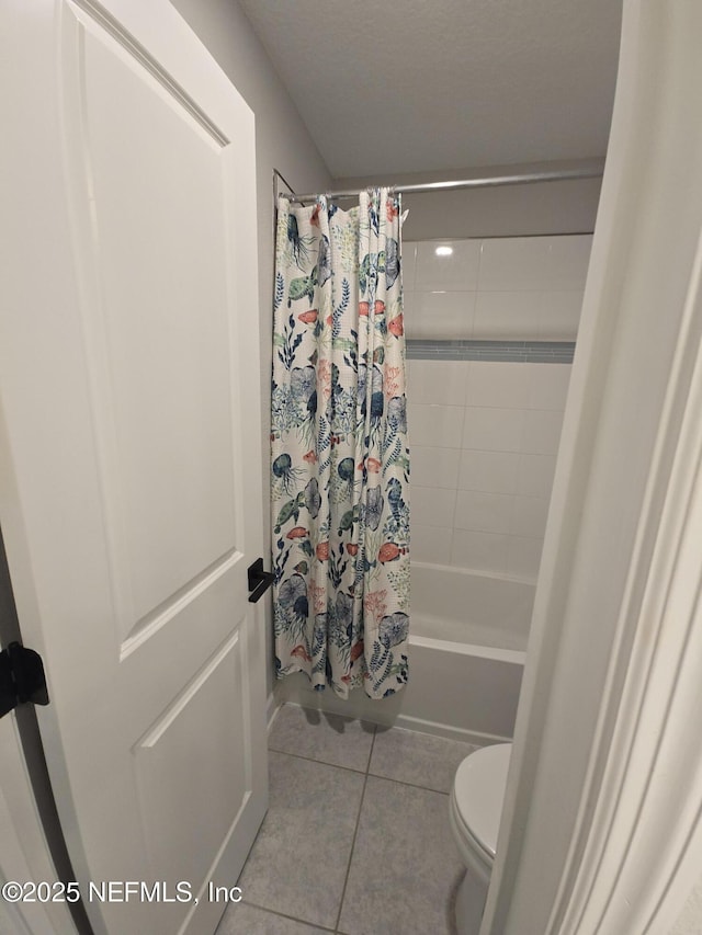 bathroom with tile patterned floors, toilet, and shower / tub combo with curtain