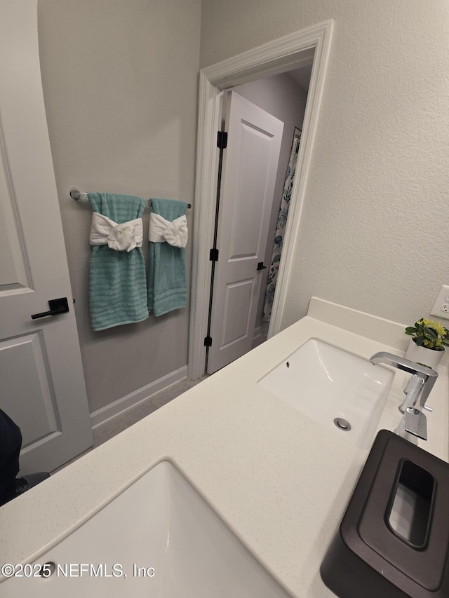 bathroom featuring a sink, baseboards, and a textured wall