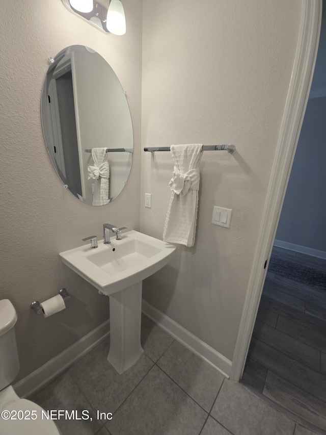 half bathroom with tile patterned floors, baseboards, and toilet