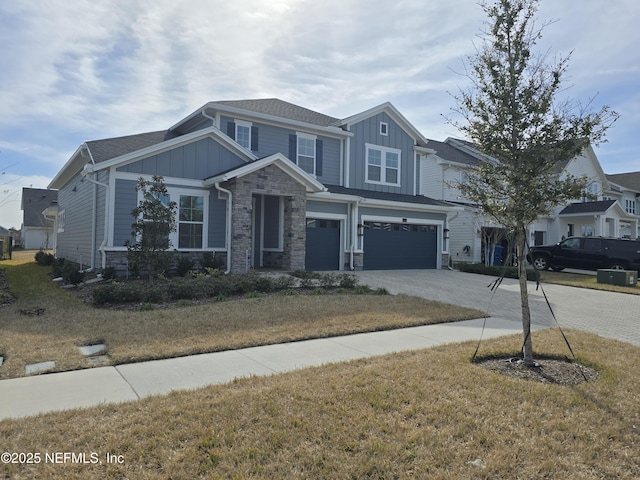 view of front of home with stone siding, board and batten siding, an attached garage, and driveway