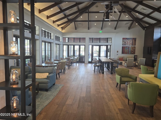 living area with visible vents, beamed ceiling, high vaulted ceiling, hardwood / wood-style floors, and ceiling fan