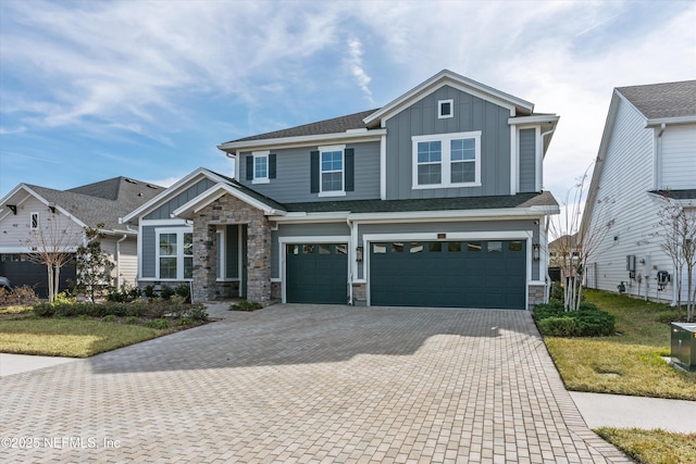 craftsman house featuring roof with shingles, stone siding, board and batten siding, decorative driveway, and a garage