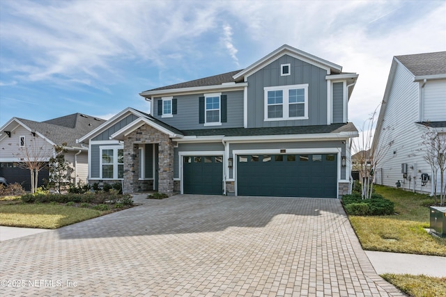 craftsman house with board and batten siding, roof with shingles, decorative driveway, stone siding, and an attached garage