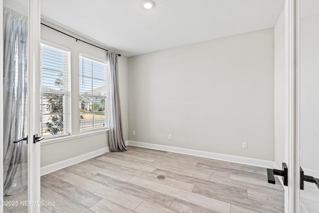 unfurnished room with french doors and light wood-type flooring