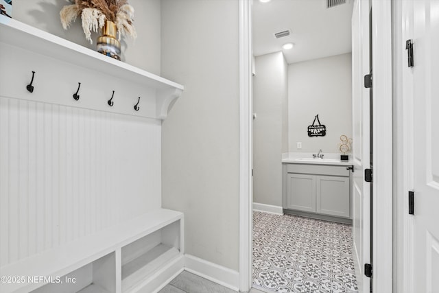 mudroom with visible vents, baseboards, and a sink