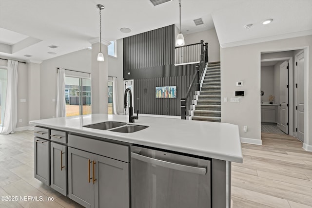 kitchen featuring gray cabinets, pendant lighting, sink, a kitchen island with sink, and stainless steel dishwasher