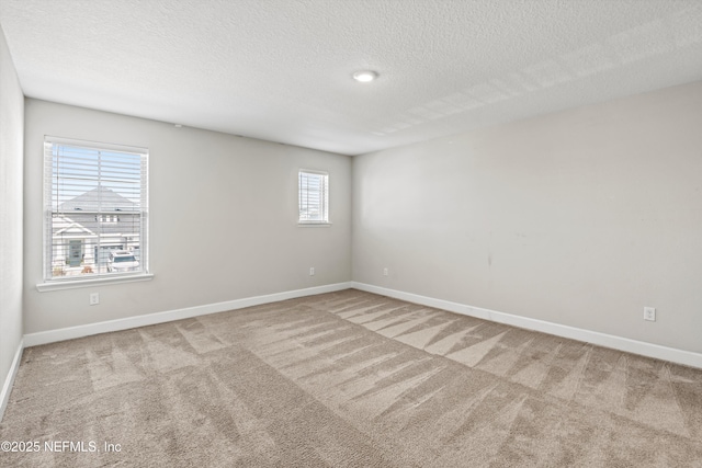 carpeted empty room featuring a textured ceiling and baseboards