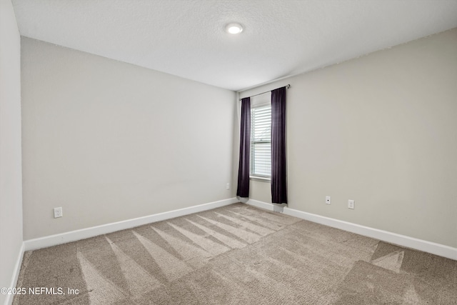 empty room featuring carpet flooring, baseboards, and a textured ceiling