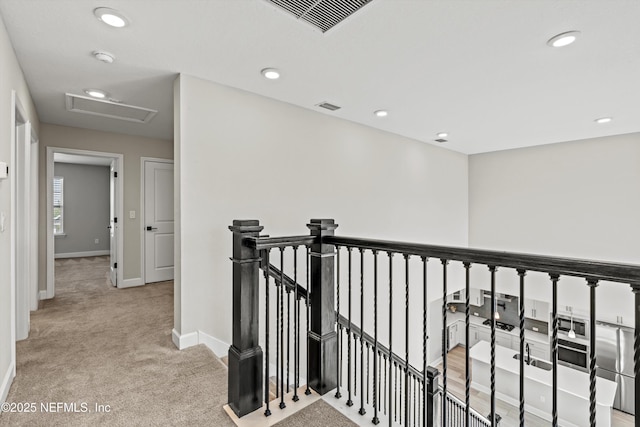 hall featuring visible vents, an upstairs landing, carpet floors, and attic access