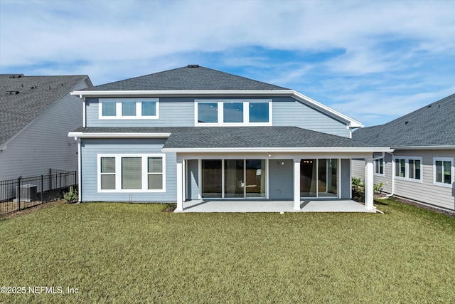 rear view of property featuring a lawn, a patio, roof with shingles, and fence