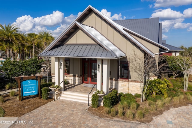 view of front of home with a standing seam roof, covered porch, stone siding, board and batten siding, and metal roof