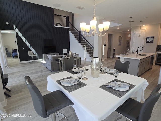 dining space with visible vents, a chandelier, wine cooler, stairs, and light wood-type flooring