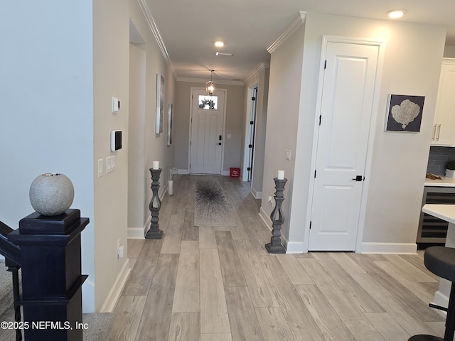 foyer with baseboards, an inviting chandelier, light wood-style flooring, wine cooler, and crown molding