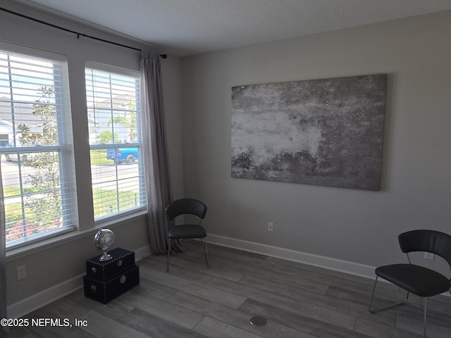 sitting room featuring wood finished floors, baseboards, and a wealth of natural light