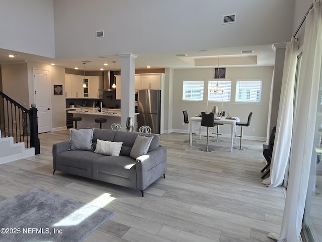 living area featuring visible vents, baseboards, stairs, and light wood-style floors