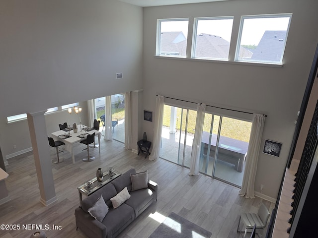 unfurnished living room featuring visible vents, light wood-type flooring, a wealth of natural light, and baseboards