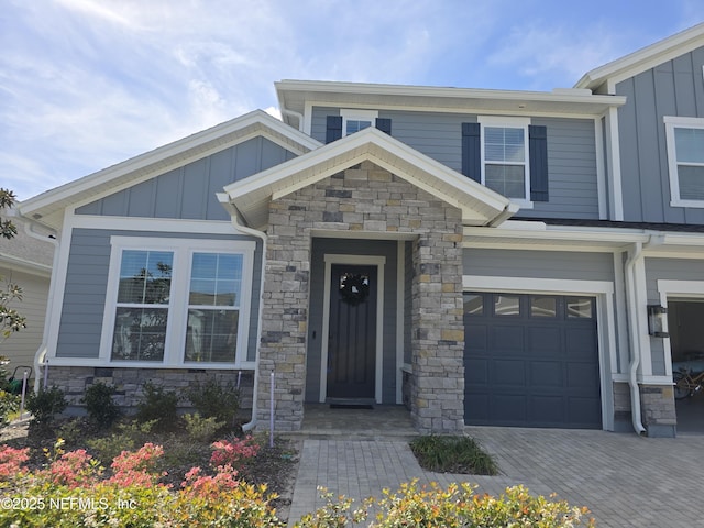 view of front of home featuring stone siding, board and batten siding, and a garage