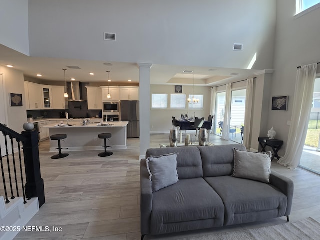 living room featuring light wood-style flooring, a chandelier, and visible vents