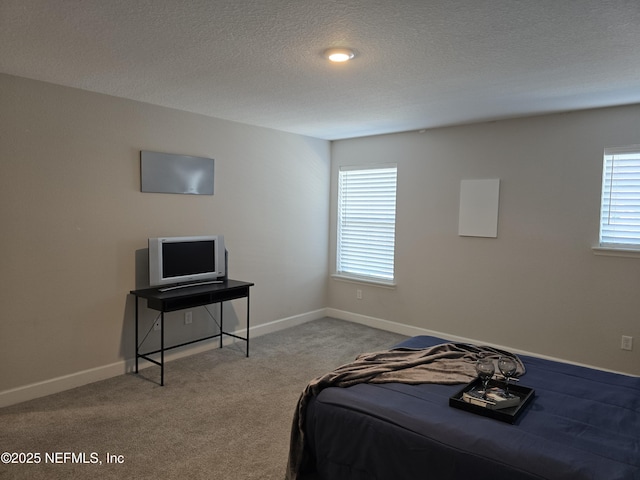 carpeted bedroom featuring baseboards, a textured ceiling, and multiple windows