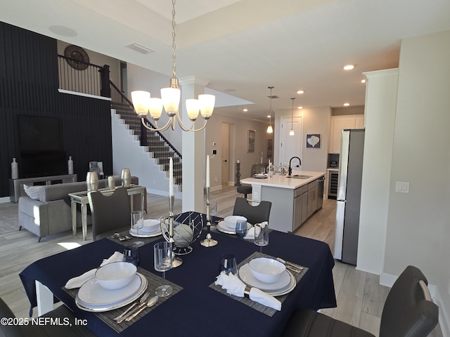 dining area with stairs, light wood finished floors, visible vents, recessed lighting, and an inviting chandelier