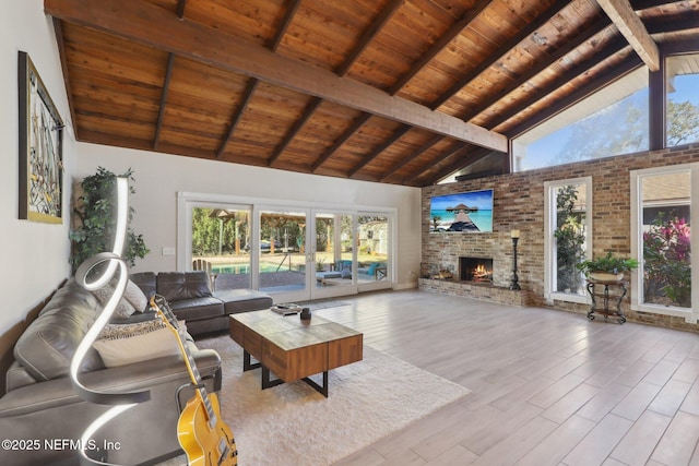 living room with wood ceiling, a stone fireplace, high vaulted ceiling, and beamed ceiling