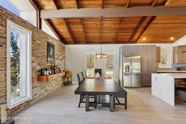 dining area featuring brick wall, a wealth of natural light, and vaulted ceiling with beams