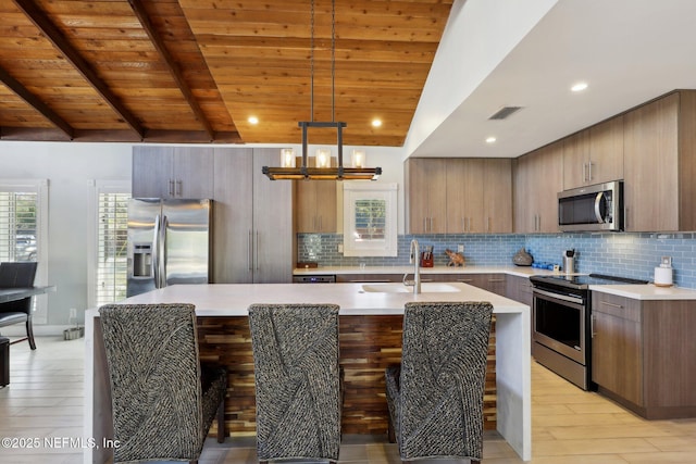 kitchen featuring sink, wood ceiling, appliances with stainless steel finishes, hanging light fixtures, and a wealth of natural light