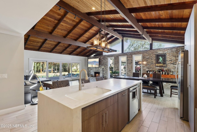 kitchen with brick wall, lofted ceiling with beams, sink, wood ceiling, and a center island with sink