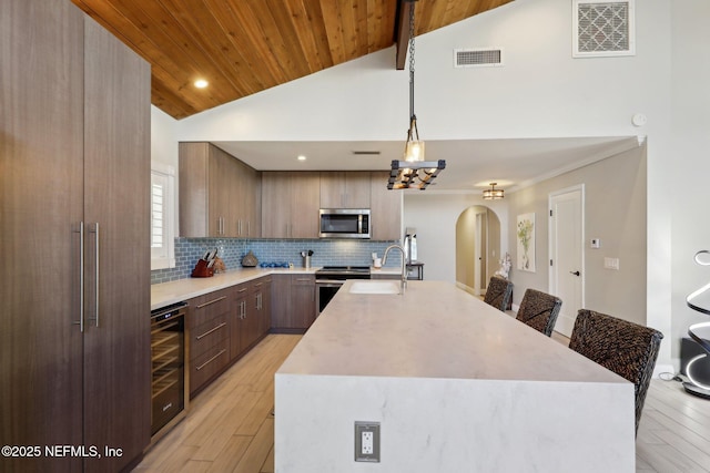 kitchen with wood ceiling, stainless steel appliances, a breakfast bar, and beverage cooler