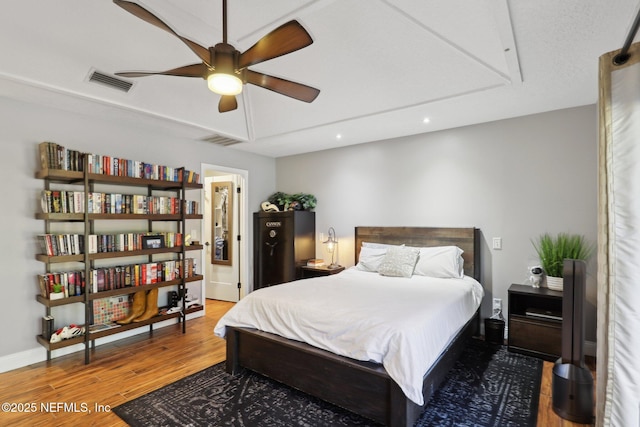 bedroom with ceiling fan, ensuite bath, and hardwood / wood-style flooring