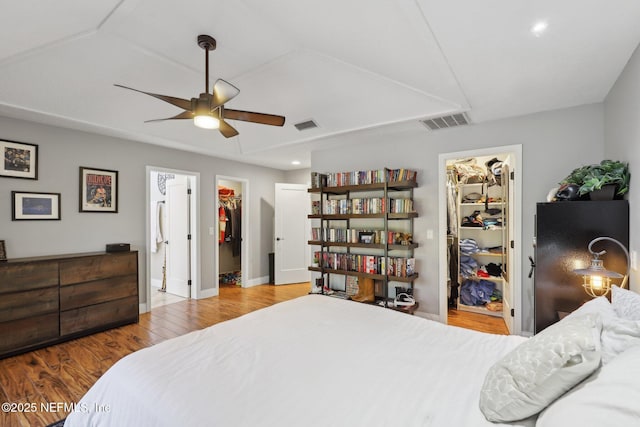 bedroom featuring ensuite bathroom, a walk in closet, light hardwood / wood-style flooring, a closet, and ceiling fan