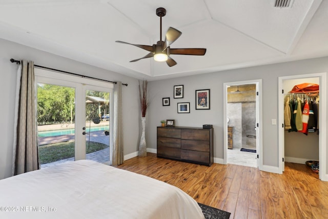 bedroom featuring light wood-type flooring, a walk in closet, ceiling fan, ensuite bath, and a closet