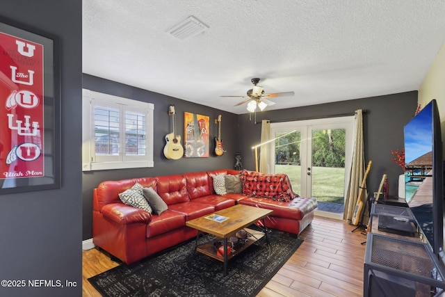 living room featuring french doors, ceiling fan, and a textured ceiling