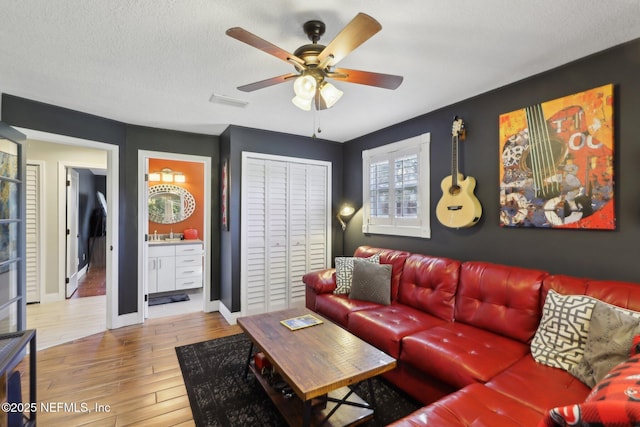 living room with hardwood / wood-style floors, a textured ceiling, and ceiling fan