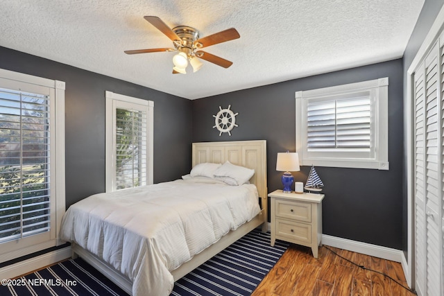 bedroom featuring hardwood / wood-style flooring, ceiling fan, multiple windows, and a textured ceiling