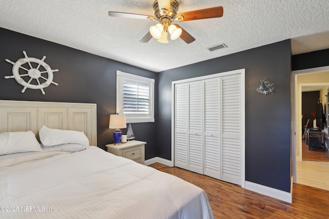 bedroom featuring ceiling fan, dark hardwood / wood-style flooring, a closet, and a textured ceiling