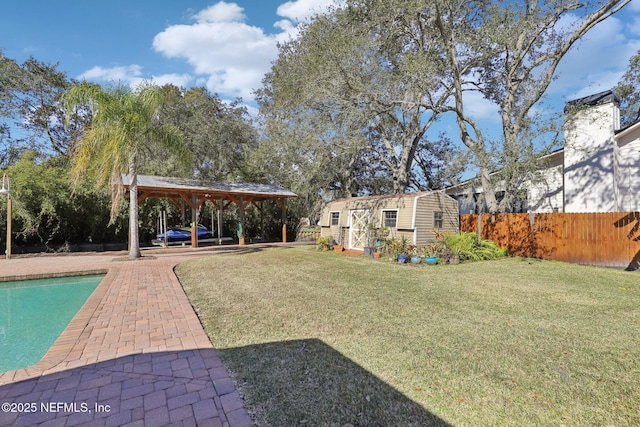 view of yard with a fenced in pool, a gazebo, and a storage unit